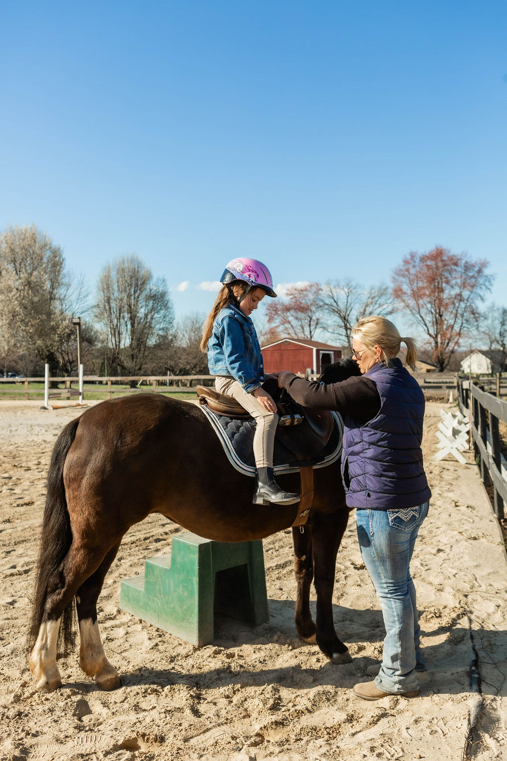 Olivia helping a young camper get settled on their horse
